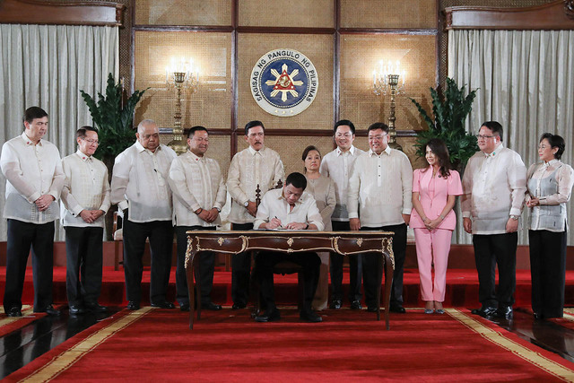 LANDMARK LAW. President Rodrigo Roa Duterte leads the ceremonial signing of the Universal Health Care Act, with congressional leaders and some lawmakers who spearheaded the bill. Malacaang photo 